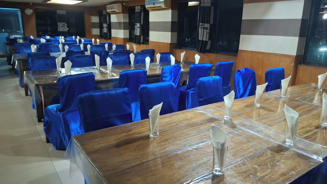 A conference room with rows of tables and chairs, each with a clear glass and a white napkin holder.
