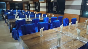 Une salle de conférence avec des rangées de tables et de chaises, chacune étant équipée d’un verre transparent et d’un porte-serviettes blanc.