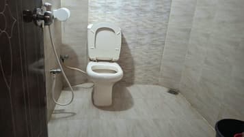 Ein Badezimmer mit Toilette, Dusche und einem Wandarmaturen-Wasserhahn.