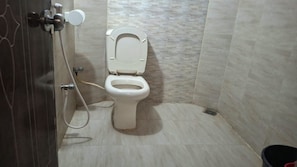 A bathroom with a toilet, shower, and a wall-mounted faucet.