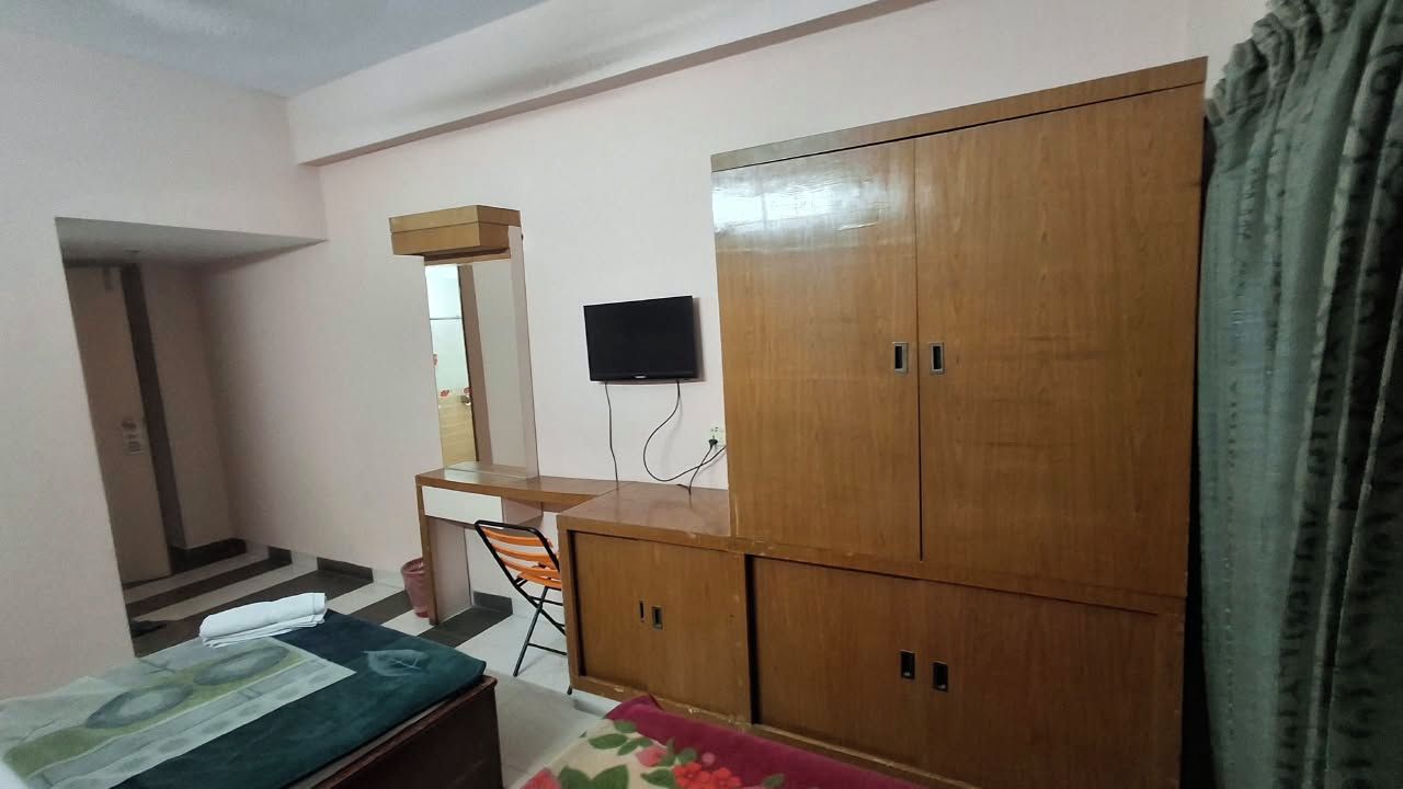Ein Schlafzimmer mit Bett, Schreibtisch, Kleiderschrank und Fernseher.