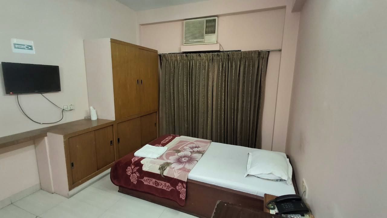 Un dormitorio con cama, armario, televisión montada en la pared y aire acondicionado.