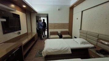 Habitación de hotel con cama, televisor montado en la pared y una zona de estar con un banco.