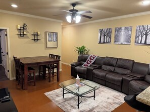 A living room with a dining table, leather sofa, and a glass coffee table. - 3 Bedrooms - 3 Bathrooms, 7 min to Texas A&M (College Station)