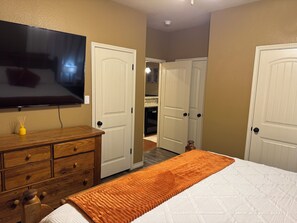 A bedroom with a bed, dresser, television, and two doors leading to other rooms. - 3 Bedrooms - 3 Bathrooms, 7 min to Texas A&M (College Station)