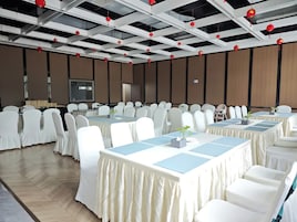 Un salón de conferencias con sillas blancas, mesas y adornos colgantes rojos.