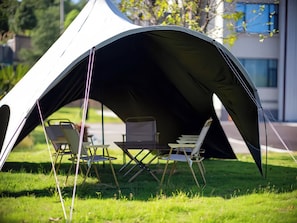 A tent with a table and chairs set up on a grassy area.