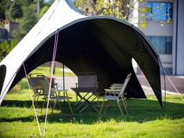 A tent with a table and chairs set up on a grassy area.
