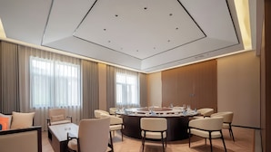 A modern conference room with a round table, multiple chairs, and a large window with curtains. - Tianmen Skyview Hotel (Zhangzhou)