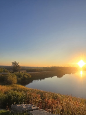 Eine friedliche Seenlandschaft mit blauem Himmel, ruhigem Wasser, das die Umgebung spiegelt, und weiter Ferne.