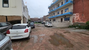 A narrow street with parked cars and buildings on either side. - Hotel A.P. Palace (Agra)