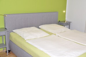 A bed with a grey headboard, two pillows, and a green bedspread. - Vacation Rental: 78 square meters, 1 separate room Bedroom, outdoor seating area, patio (Burghausen)
