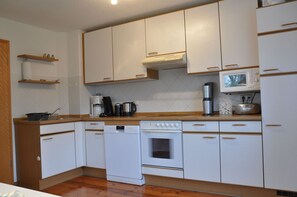 A compact kitchen with white cabinets, a built-in oven, a microwave, and a coffee maker. - Vacation Rental: 78 square meters, 1 separate room Bedroom, outdoor seating area, patio (Burghausen)