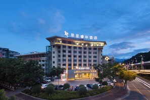 A hotel with a modern facade, multiple floors, and a parking lot with several cars. - Cloud Grand View Sky Gate Resort (Zhangzhou)
