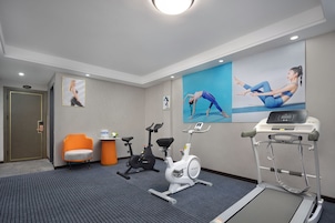 Un gimnasio con equipo de ejercicio, una cinta de correr y una bicicleta estática.