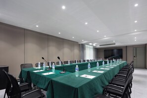 A conference room with a long table, chairs, microphones, and water bottles.