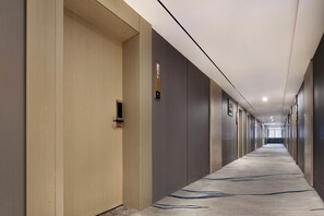 A long, narrow hotel corridor with a carpeted floor, wooden and grey walls, and a series of doors on one side. - Cloud Grand View Sky Gate Resort (Zhangzhou)