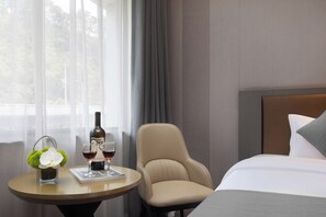 A hotel room with a bed, a round table with a bottle and glasses, a chair, and a window with curtains. - Cloud Grand View Sky Gate Resort (Zhangzhou)