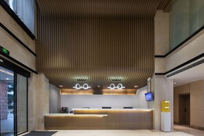 Una moderna zona de recepción con techo de madera, mostrador de recepción y pantalla digital.