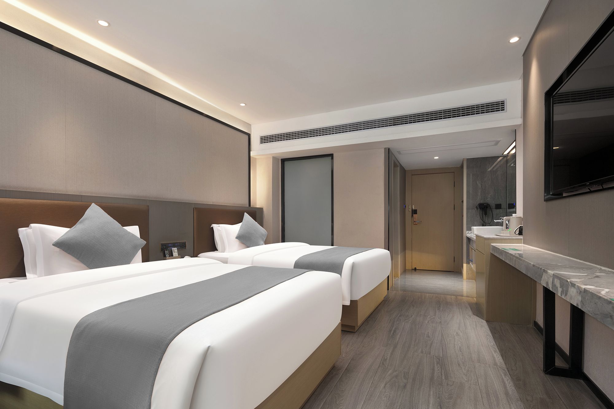 Habitación de hotel con dos camas, baño y televisión.