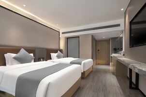 Habitación de hotel con dos camas, baño y televisión.