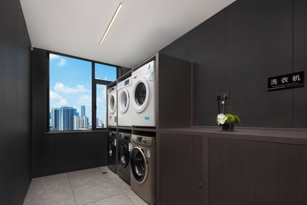 A modern laundry room with two washing machines, a large window with a city view, and a sign indicating the location. - Cloud Grand View Sky Gate Resort (Zhangzhou)