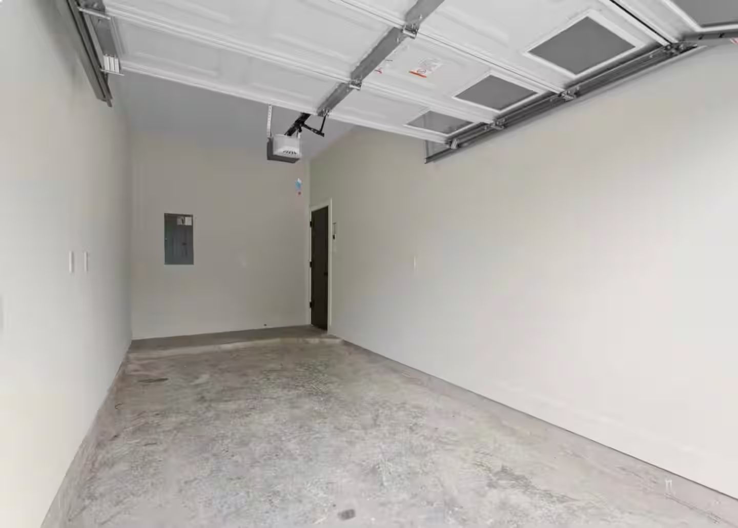 A hallway with a garage door, a door, and a small sign on the wall.
