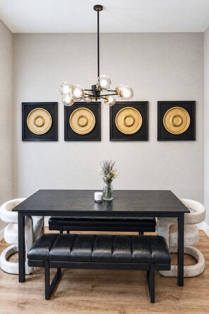 A dining area with a black table, bench, and a chandelier. - Entire duplex | Two homes, one stay (Houston)