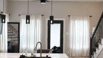 A modern kitchen with a central island, pendant lights, a ceiling fan, and a stainless steel dishwasher.