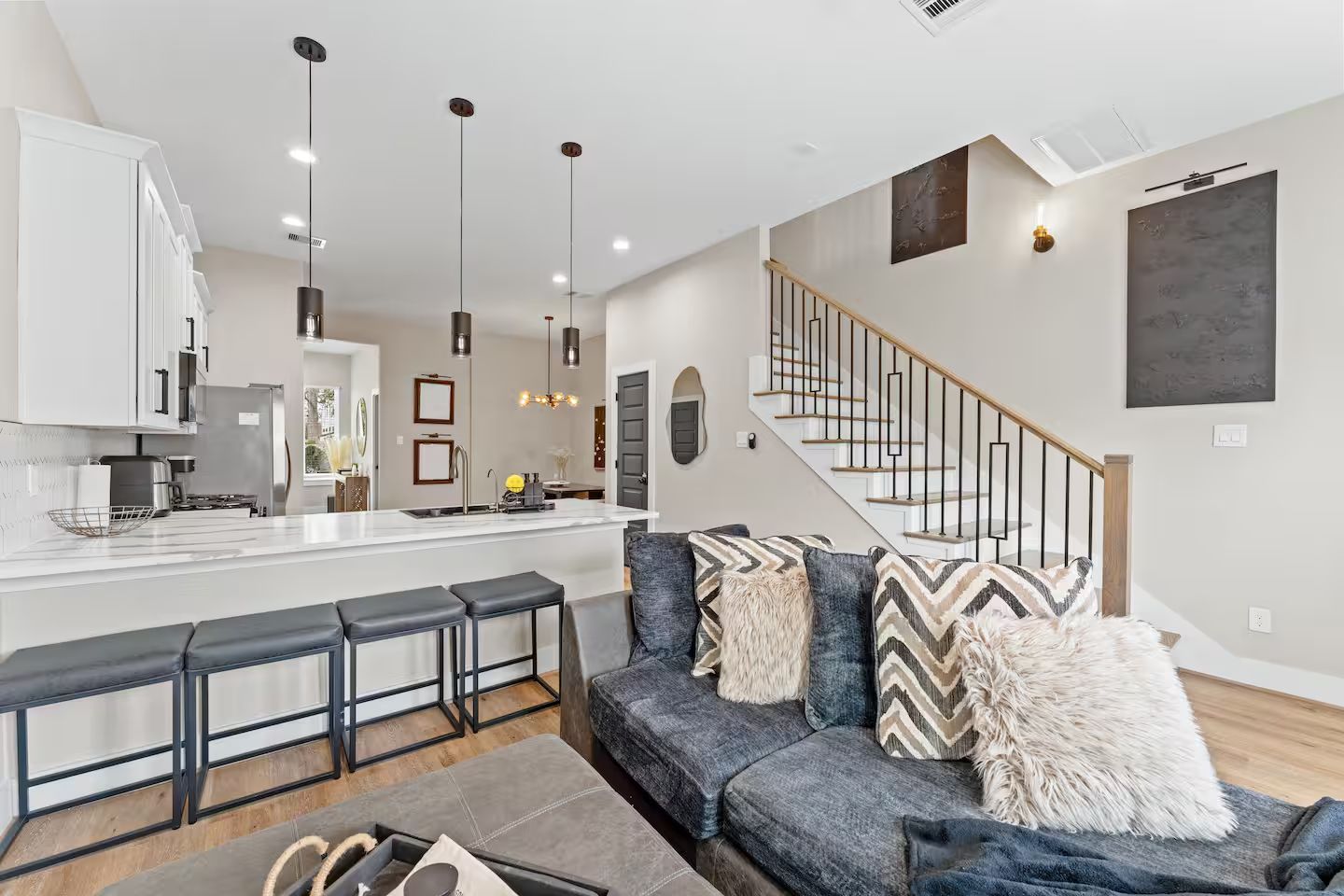 A modern kitchen with a central island, bar stools, and pendant lighting.