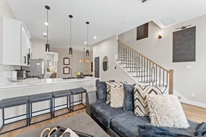 A modern kitchen with a central island, bar stools, and pendant lighting. - Entire duplex | Two homes, one stay (Houston)