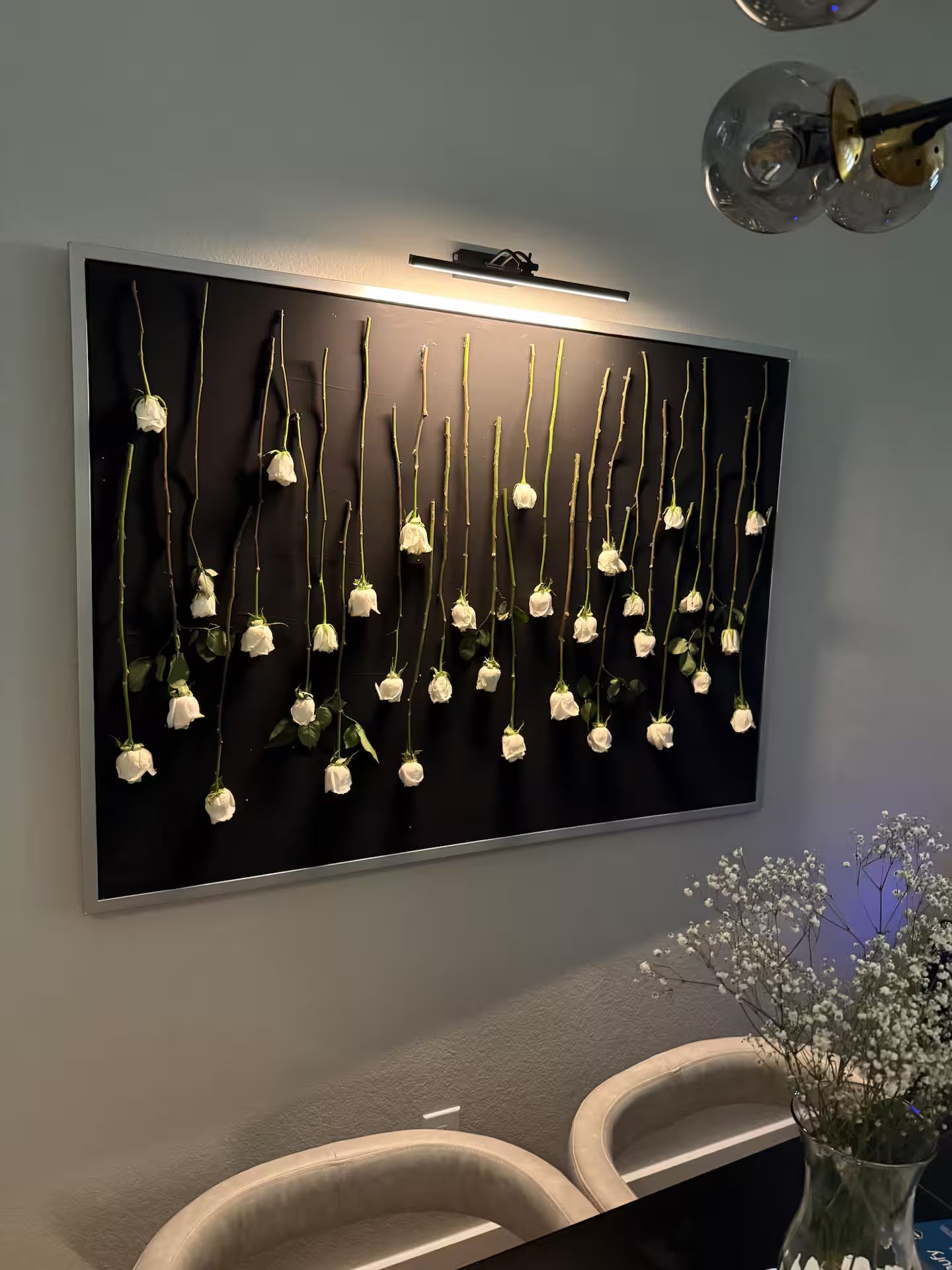 A wall-mounted art piece with white roses and stems.