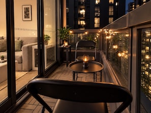 A balcony with a table and chairs, a potted plant, and string lights. - Melbourne Paws Escape | Pool, Gym & Sauna (Melbourne)