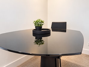 A round table with a black surface and a single potted plant in the center. - Melbourne Paws Escape | Pool, Gym & Sauna (Melbourne)