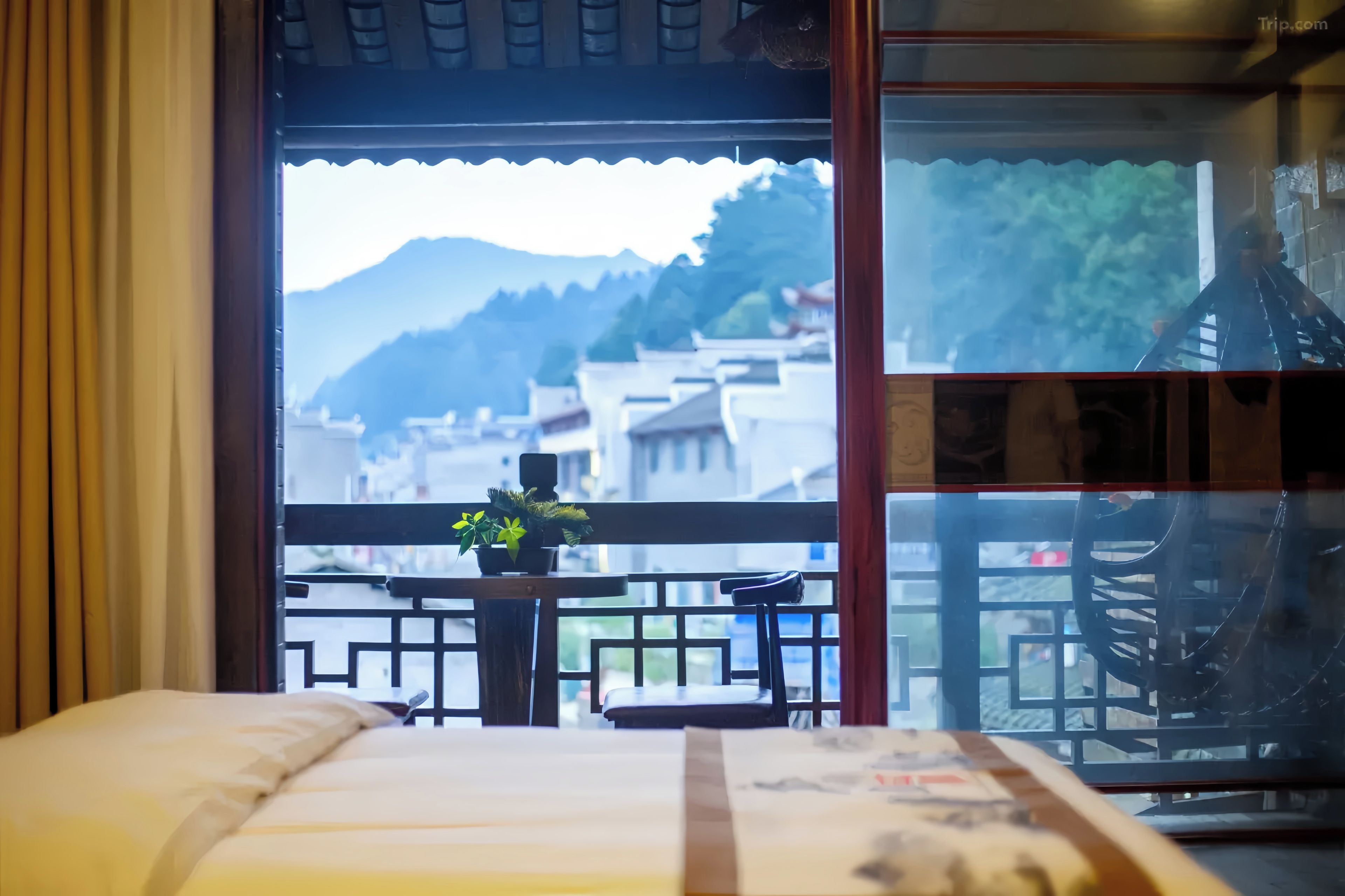 Una habitación con cama, una mesa con planta en maceta y vistas a un paisaje montañoso a través de una ventana.