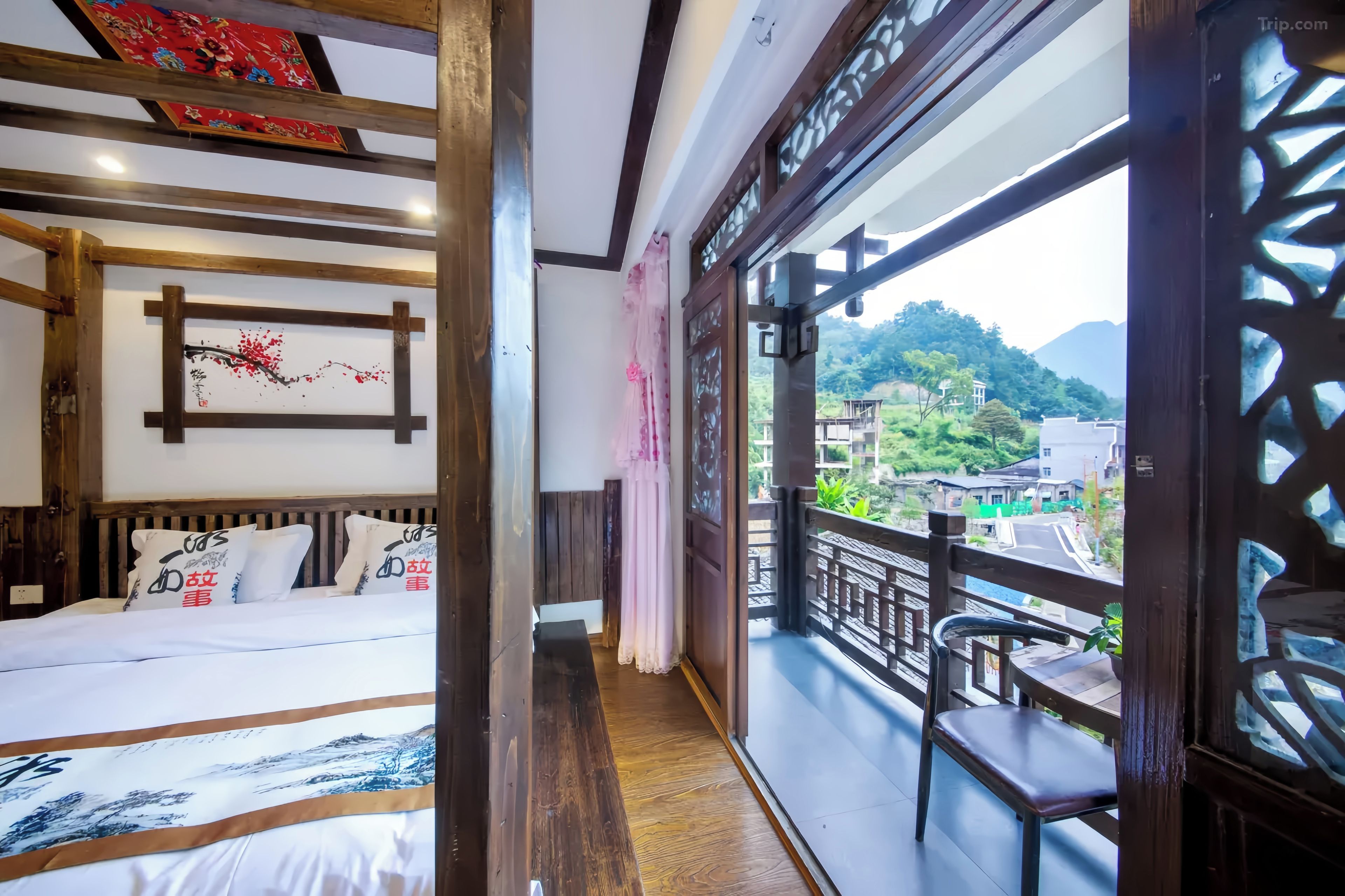 Un dormitorio con cama, cabecera de madera y vistas a un balcón con una silla.