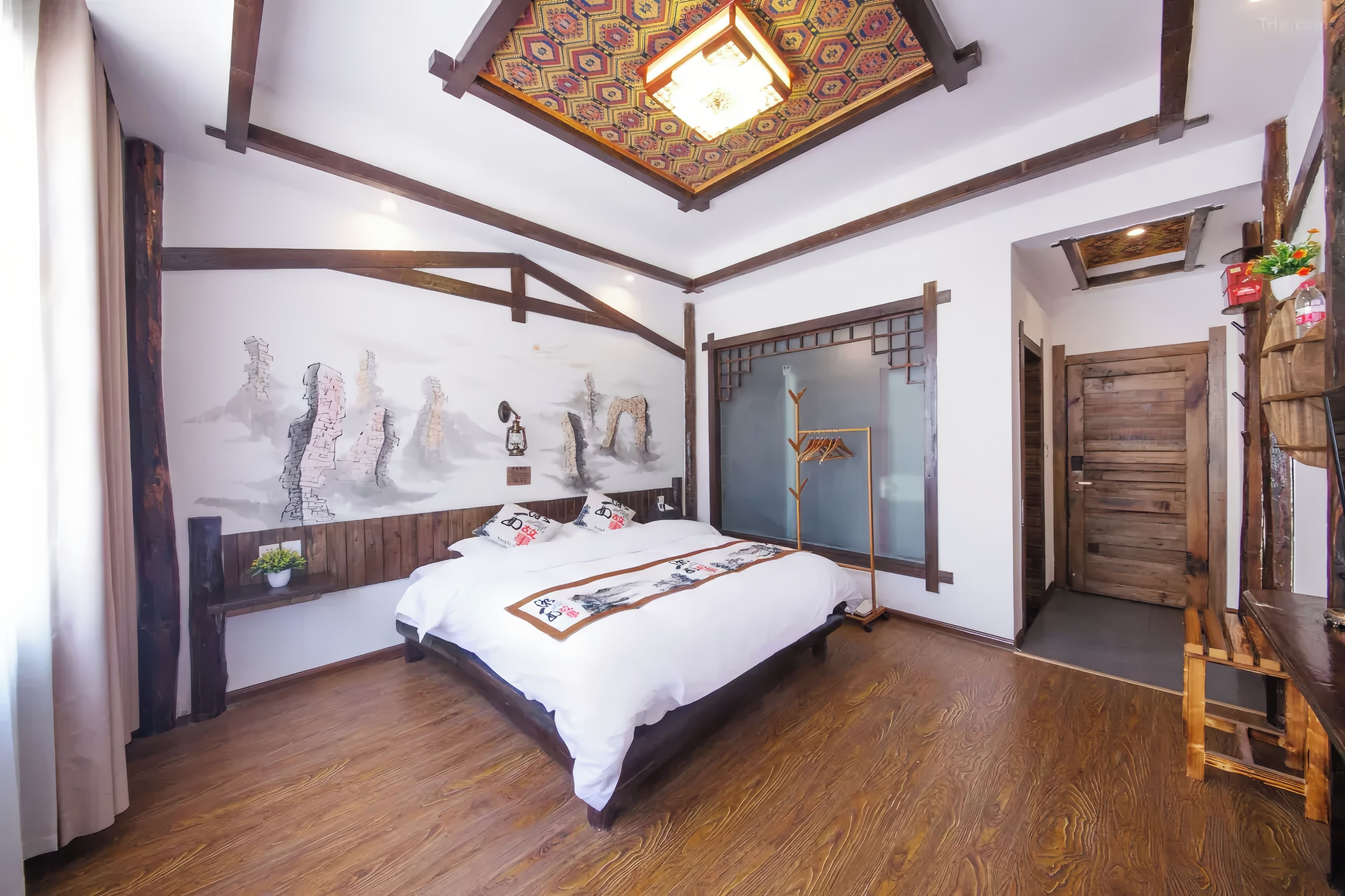A bedroom with a wooden bed, a decorative wall, and a traditional ceiling design.
