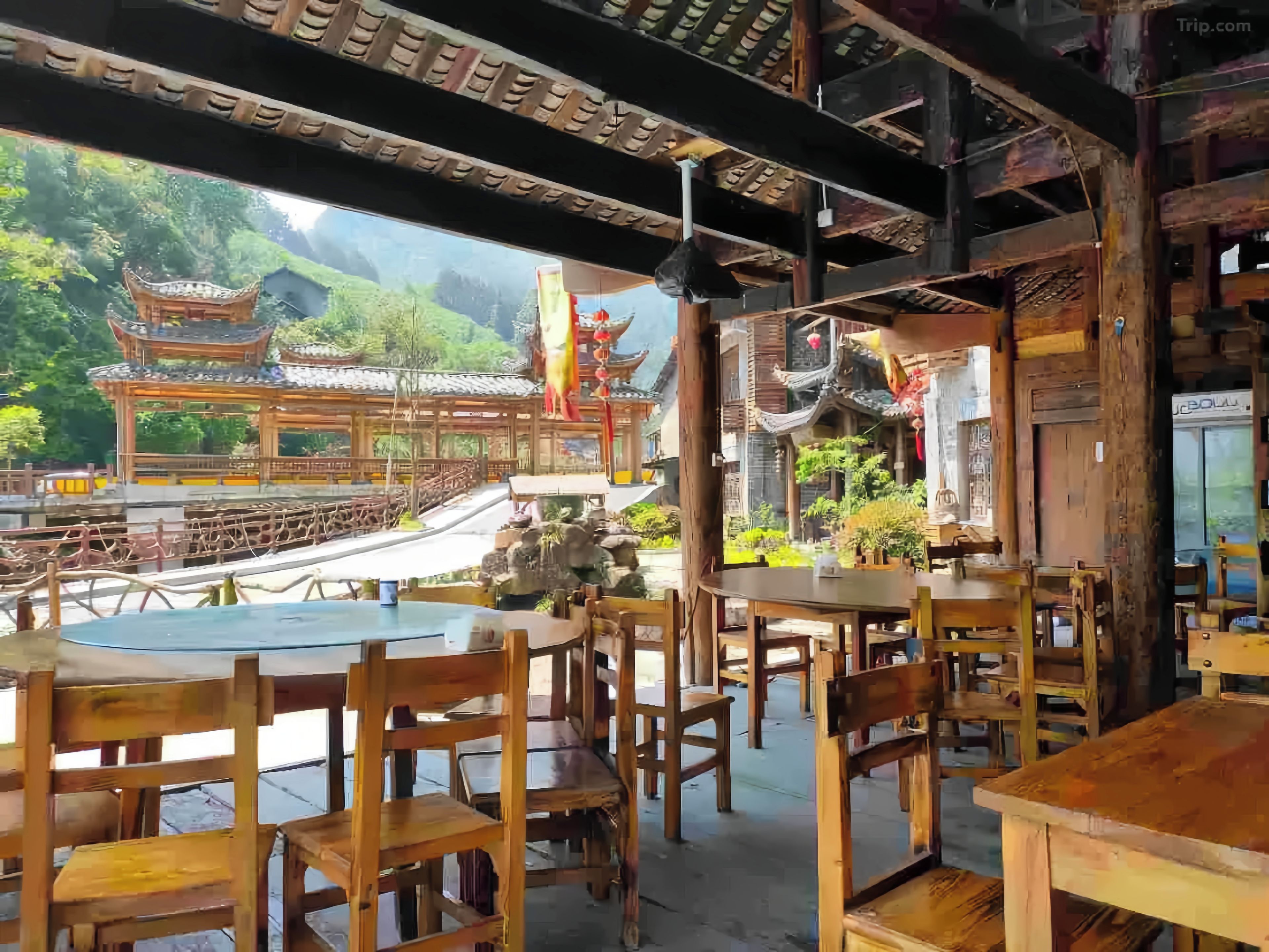 A traditional wooden structure with a view of a multi-tiered building and greenery.