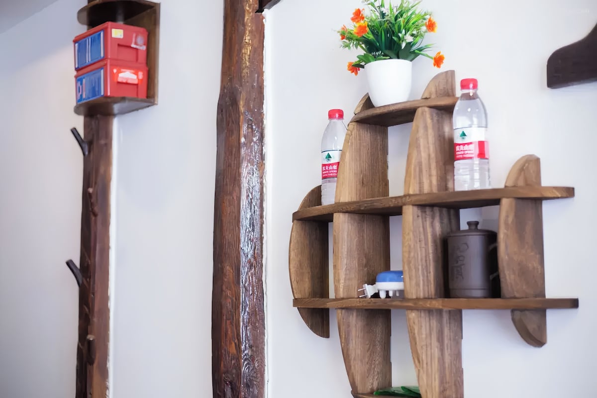 Una estantería de madera con una planta en maceta, dos botellas y un recipiente.