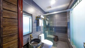 A modern bathroom with a glass shower enclosure, a toilet, and a sink with a decorative bowl.