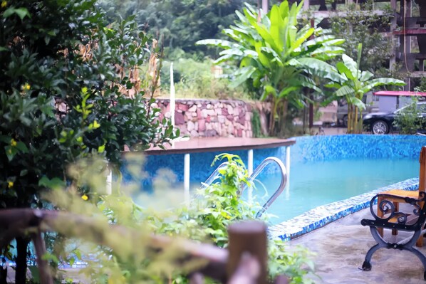 A swimming pool with a stone wall and a bench.