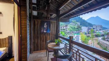 A wooden balcony with a view of a mountainous landscape and buildings.
