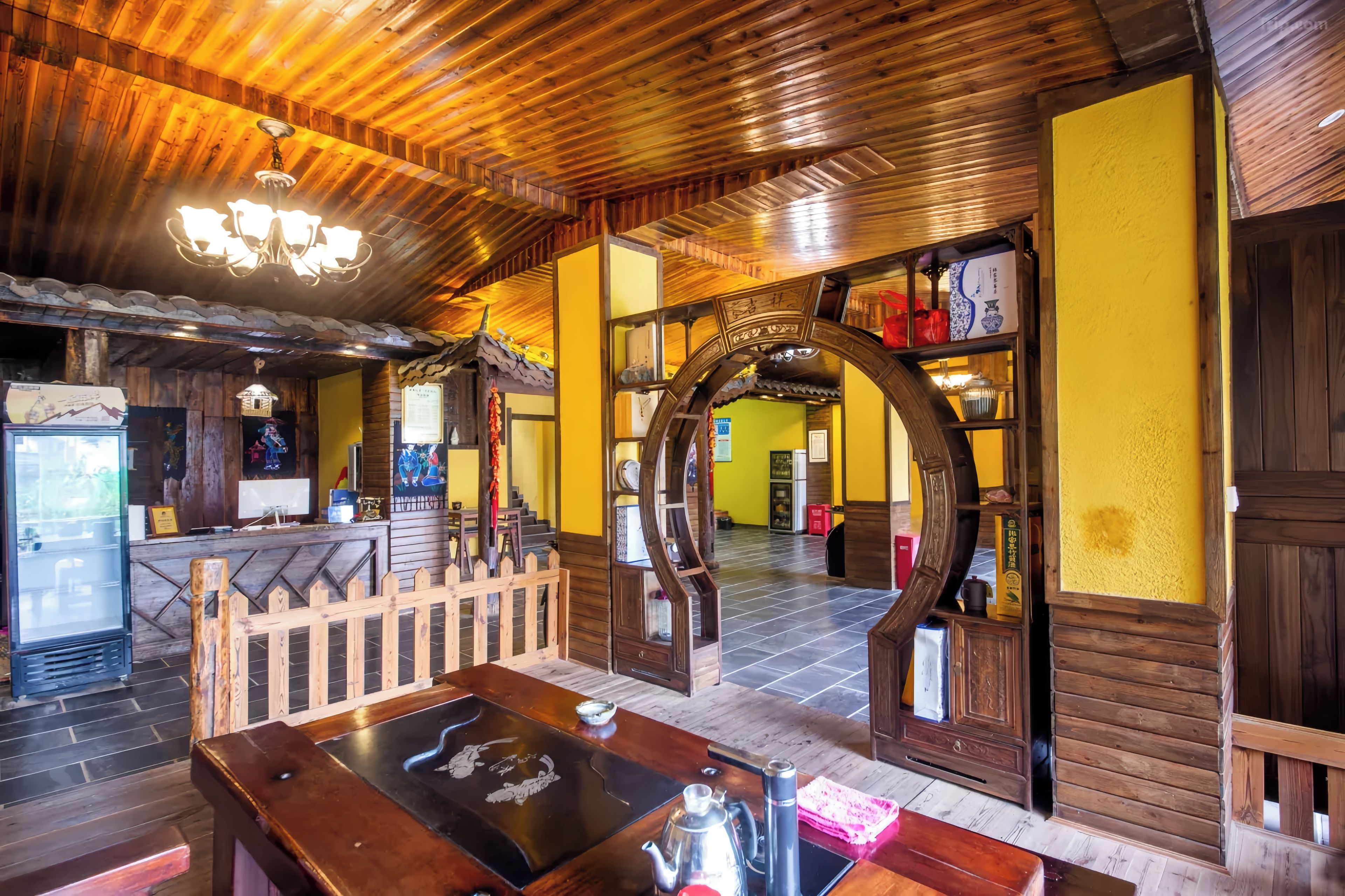 A traditional wooden interior with a reception desk, a staircase, and a decorative archway.