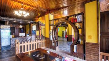 A traditional wooden interior with a reception desk, a staircase, and a decorative archway.
