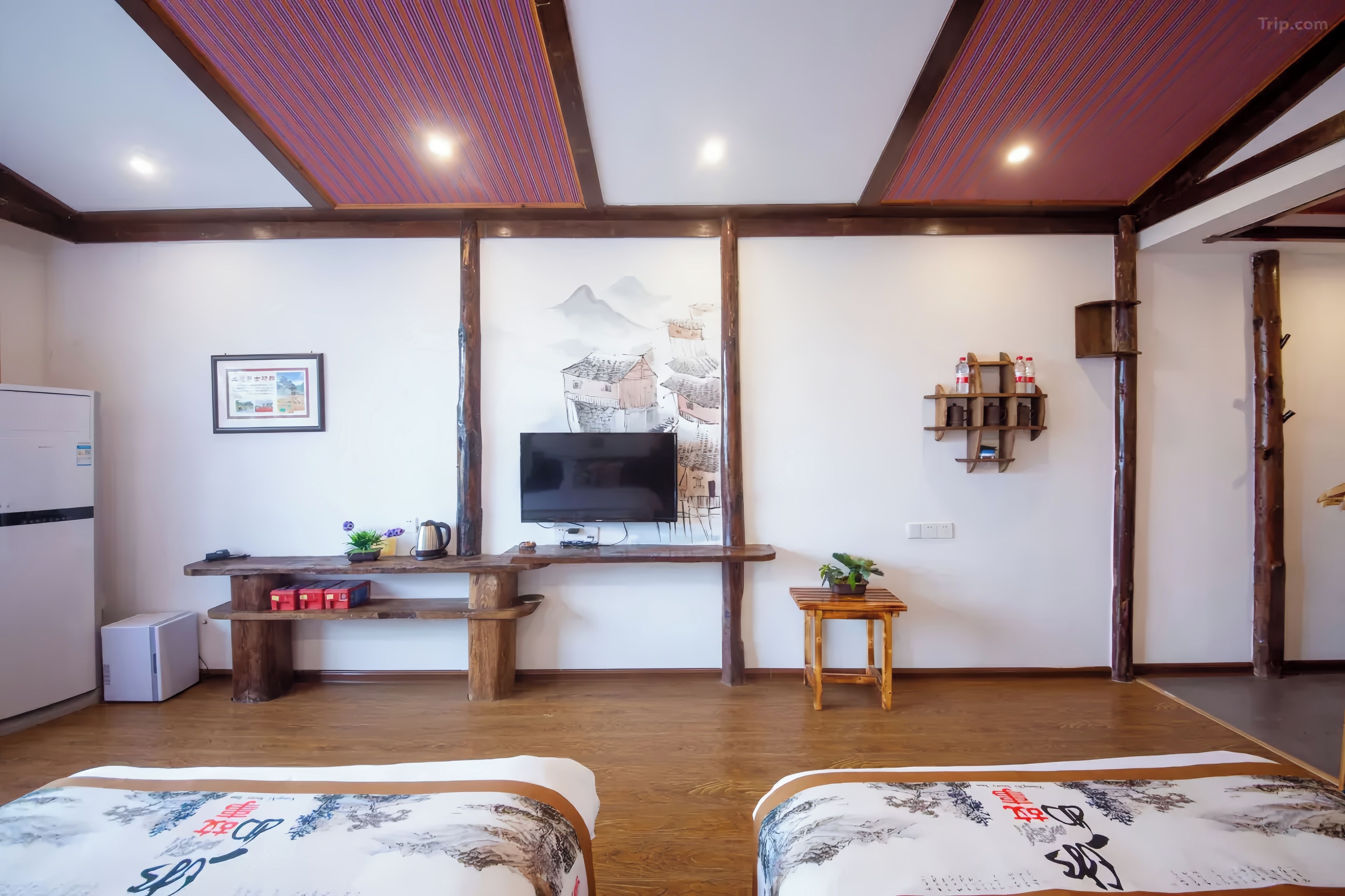 Quarto com cama, escrivaninha com televisão e prateleira na parede com garrafas.