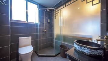 A modern bathroom with a toilet, a glass-enclosed shower, and a sink with a decorative basin.