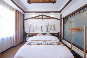 A hotel room with a bed, a wooden headboard, a wall-mounted coat rack, and a window with curtains.