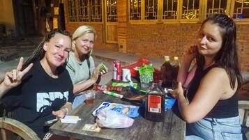 Tres personas sentadas en una mesa al aire libre, con diferentes comidas y bebidas.