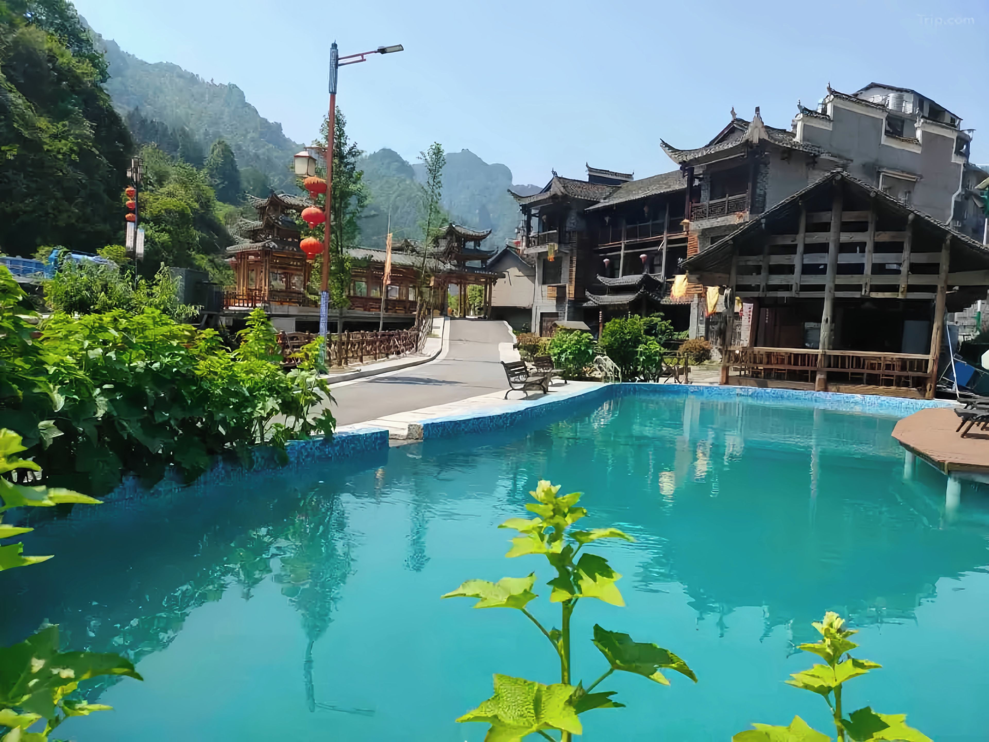 Un edificio tradicional con piscina, rodeado de vegetación y montañas.