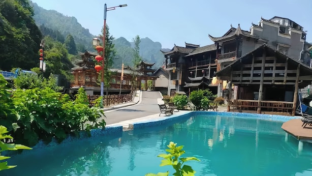 Un edificio tradicional con piscina, rodeado de vegetación y montañas.
